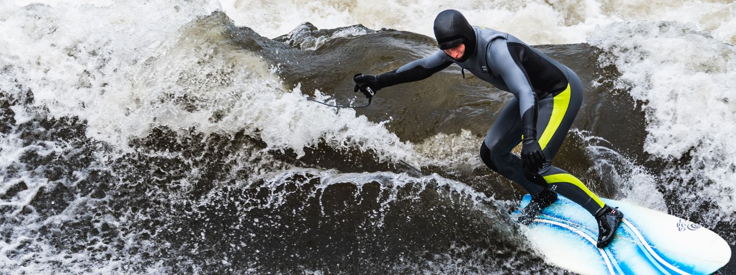 Surfer auf der Leinewelle mit einem blau-weißem Surfboard frontal fotografiert