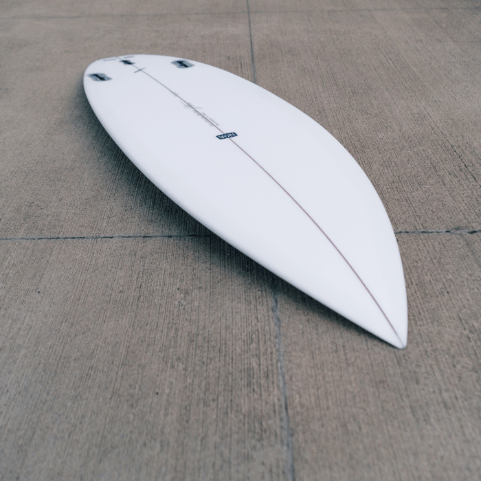 Weißes Surfboard von Noa Surfboards, dass auf dem mit dem Bottom nach oben auf dem Boden liegt