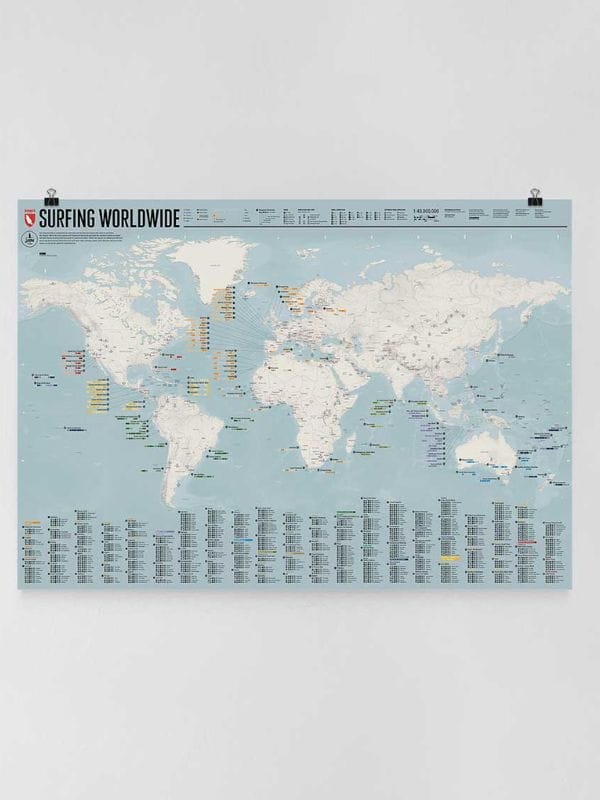 Eine Weltkarte mit der Aufschrift "Surfing Worldwide" zeigt Kontinente und Ozeane mit verschiedenen markierten Surfspots und einem detaillierten Verzeichnis der Surfdestinationen unterhalb der Karte. Die Karte ist mit zwei Clips an einer weißen Wand befestigt.