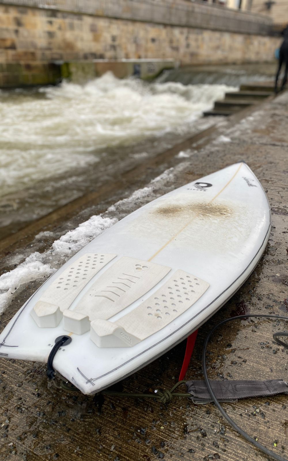 River Surfboard mit vorne Wachs und hinten einem Tailpad vor der Leinewelle liegend