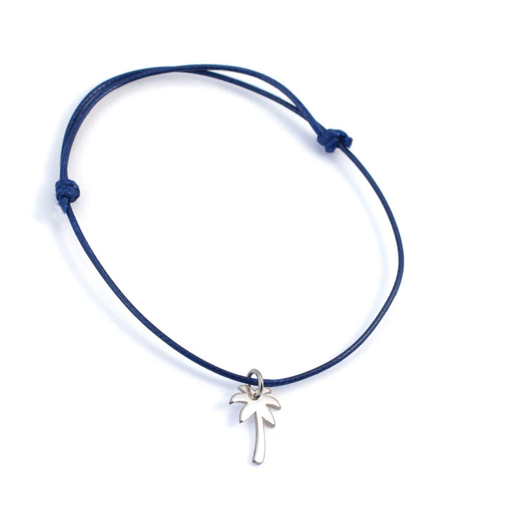Das Silver+Surf Silber Schmuck Palme ist ein blaues verstellbares Kordelarmband von Silver+Surf, mit einem kleinen silbernen Palmenanhänger, handgefertigt aus 925 Sterling Silber und abgebildet auf weißem Hintergrund.