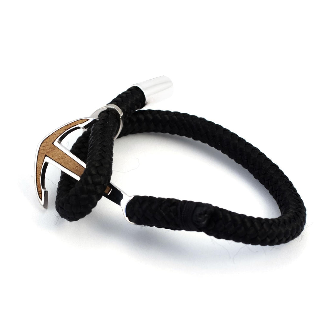 Das Silver+Surf Silber Schmuck Boot Anker Wood Armband ist ein schwarzes, geflochtenes Armband mit einem 925 Sterling Silber Anker Verschluss in Silber und Holz, abgebildet vor einem weißen Hintergrund.