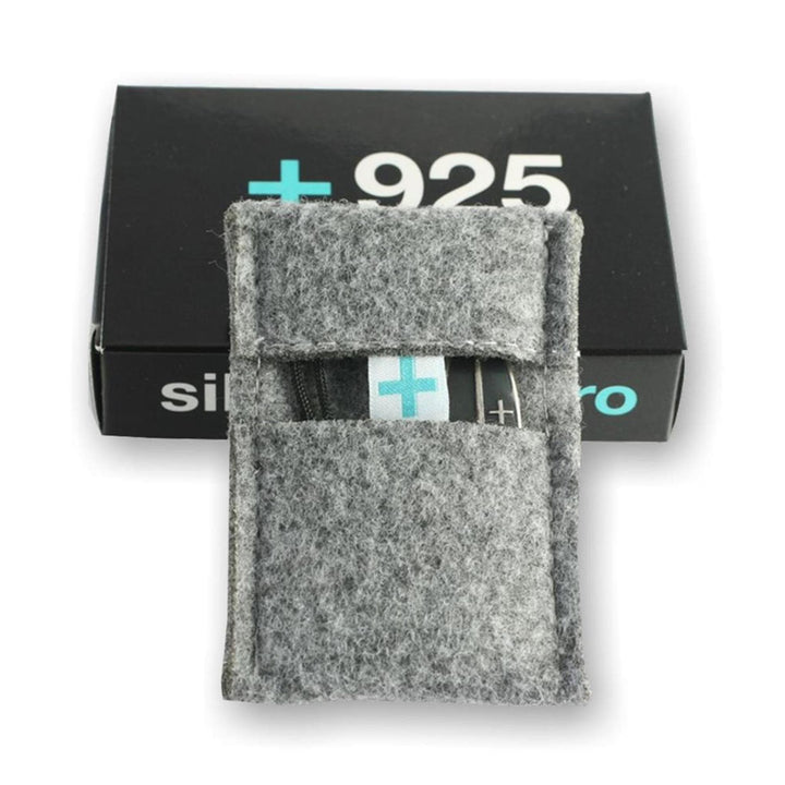 Eine kleine, rechteckige graue Filztasche hält ein Silver+Surf Silber Schmuck Love Welle Armband vor einer schwarzen Box mit der Aufschrift +925. Das Display hebt diesen eleganten 925 Sterling handgemachten Schmuck von Silver+Surf hervor.