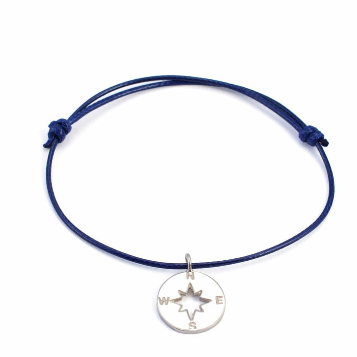 Das Silver+Surf Silber Schmuck Windrose Himmelsrichtung ist ein blaues verstellbares Kordelarmband mit einem 925 Sterling Silber Anhänger, graviert mit N, S, E, W um einen ausgeschnittenen Stern-stilvoller handgemachter Schmuck von Silver+Surf.