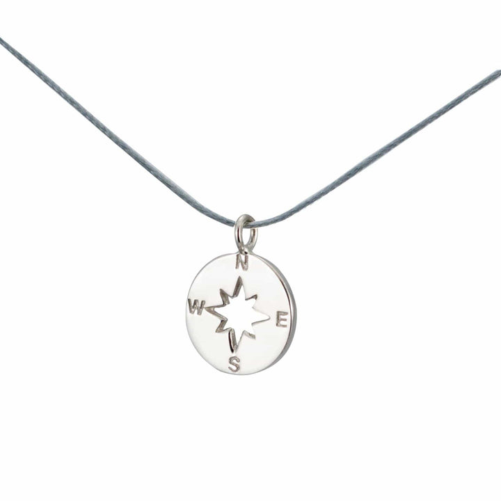 Der Silver+Surf Silber Schmuck Windrose Himmelsrichtung Anhänger aus 925 Sterling Silber mit N, E, S und W Gravur hängt an einer grauen Kordel - ein elegantes Kompass-Schmuckstück von Silver+Surf.