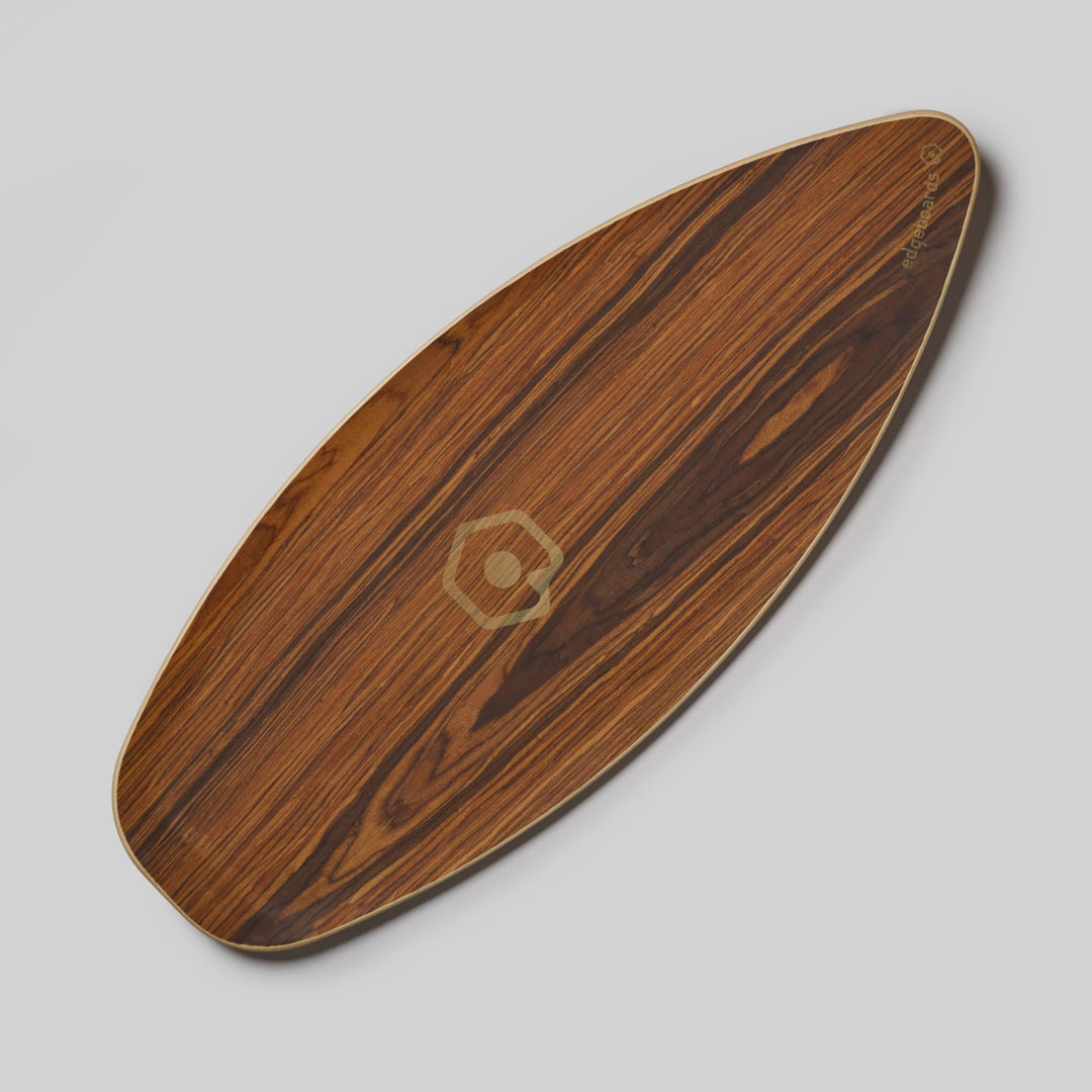 Das Edgeboards Balanceboard von Edgeboards verfügt über ein glattes, ovales Holzdesign mit einem natürlichen Holzmaserungsmuster und einem kleinen geometrischen Logo in der Mitte. Perfekt für Skatefeeling und Gleichgewichtstraining, wird es auf einem schlichten hellgrauen Hintergrund gezeigt.