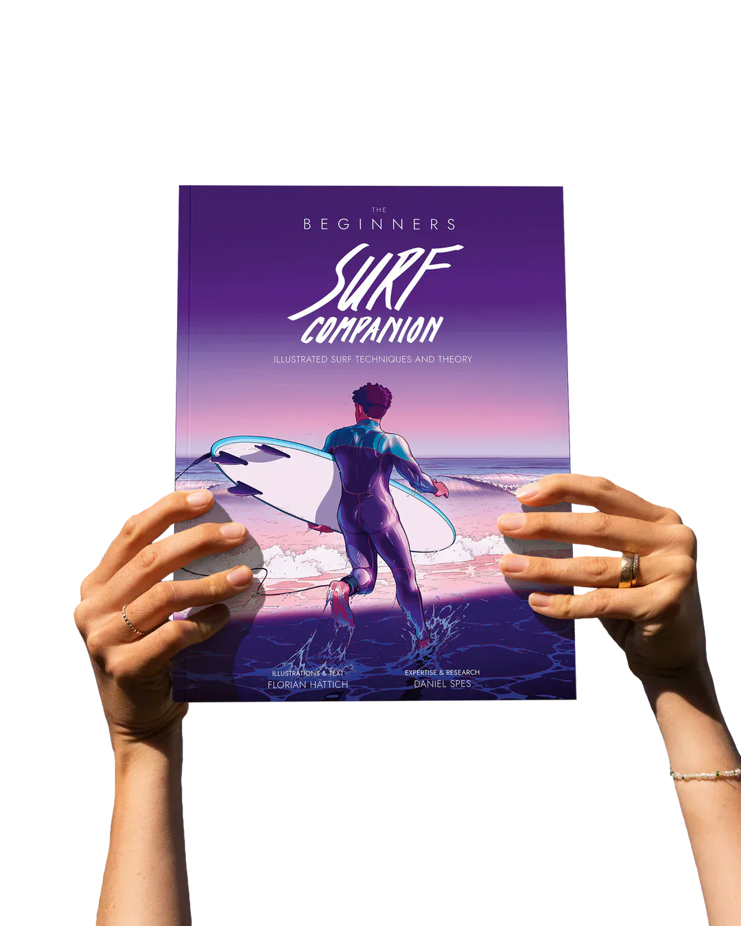 Eine Person hält das Surfcompanion Surf Companion Beginner 2. Edition - Surfbuch, ein illustriertes Arbeitsbuch für Surf-Anfänger, das einen Surfer mit Brett bei Sonnenuntergang zeigt. Beide Hände sind vor einem schlichten weißen Hintergrund zu sehen.