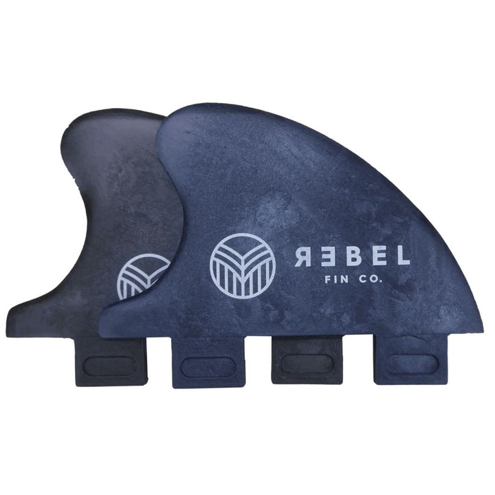 Zwei schwarze Rebel Fin X Driftwood Rapid Fin FCS I Flossen aus recyceltem Carbon mit REBEL FIN CO. und weißem, kreisförmigem Logo sind nebeneinander auf weißem Grund abgebildet.