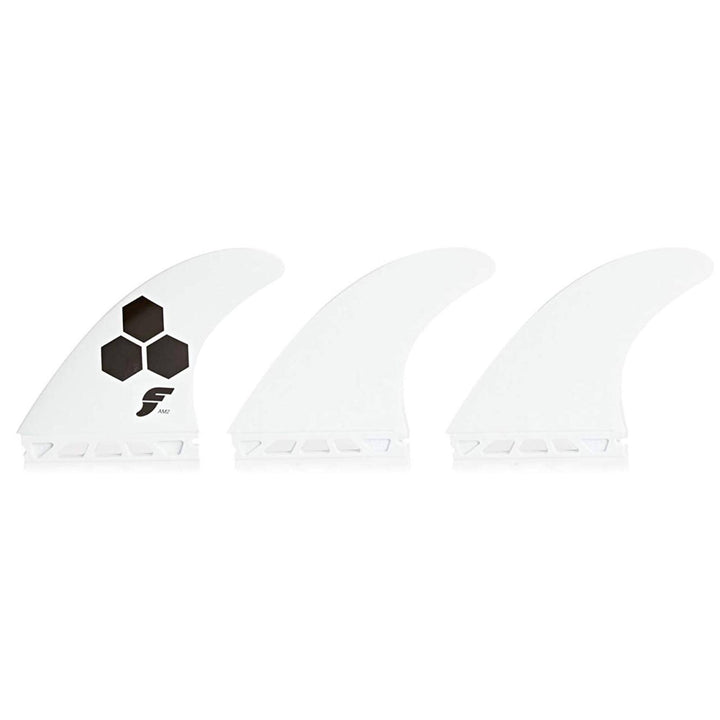Drei weiße FUTURES Thruster Finnen Set AM2 Al Merrick Thermotech Finnen von futures sind nebeneinander abgebildet; die linke Finne trägt ein schwarzes Sechseck-Logo mit einem stilisierten "F", während die beiden anderen einfarbig weiß sind.