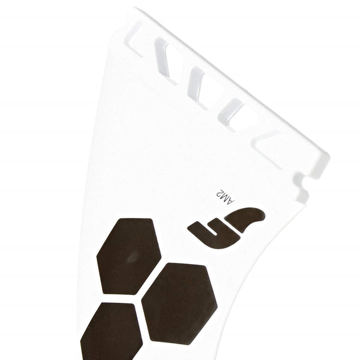 Eine Nahaufnahme einer weißen Futures FUTURES Thruster Fin Set AM2 Al Merrick Thermotech Surfboard Finne mit schwarzem Sechseck-Design und "AM2" und "F" Text, mit geschlitzten Aussparungen und der innovativen Futures Truss Base für Performance.