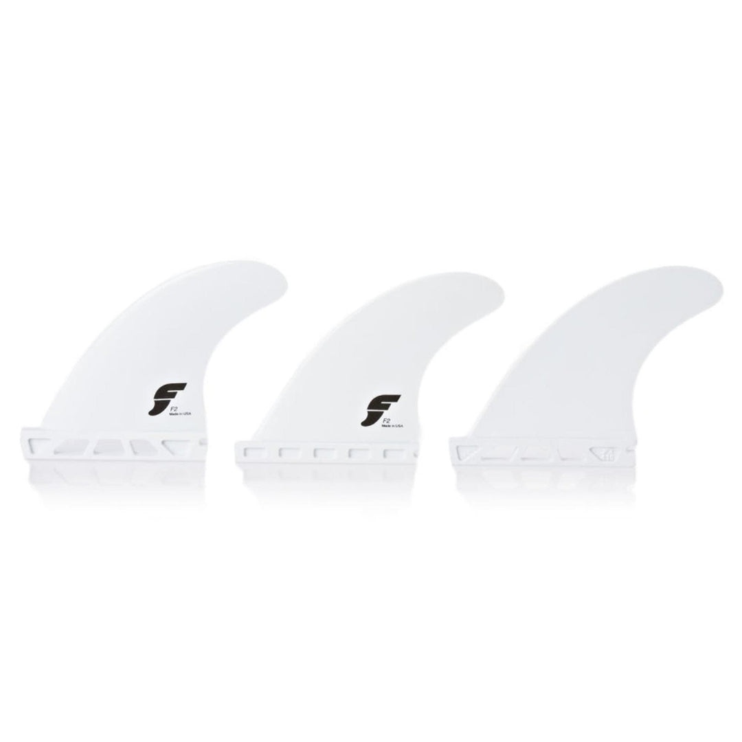 Drei weiße Futures FUTURES Thruster Fin Set F2 Thermotech X-SMALL Flossen stehen aufrecht vor einem weißen Hintergrund. Jede Flosse hat ein schwarzes F-Logo, einen geschlitzten Boden für eine einfache Befestigung und eine identische Form und Größe.