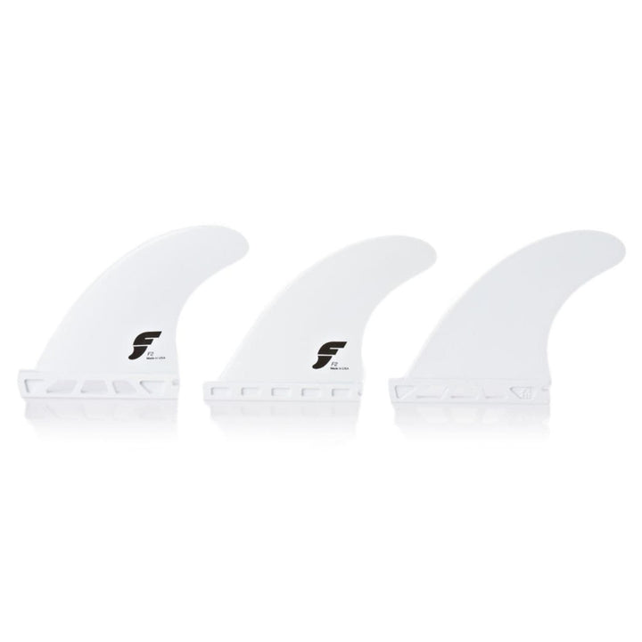 Drei weiße Futures FUTURES Thruster Fin Set F2 Thermotech X-SMALL Flossen stehen aufrecht vor einem weißen Hintergrund. Jede Flosse hat ein schwarzes F-Logo, einen geschlitzten Boden für eine einfache Befestigung und eine identische Form und Größe.