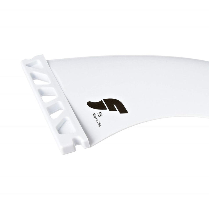 Eine Nahaufnahme einer weißen Futures FUTURES Thruster Fin Set F6 Thermotech M Surfboard-Finne mit geschlitzter Basis, die den Buchstaben F, den Text "F6" und "Made in USA" auf einem schlichten weißen Hintergrund zeigt.