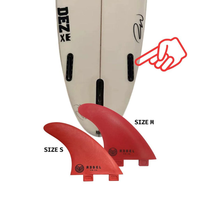 Zwei rote Rebel Fin - einzelne Finne (Glasfaser) von Rebel Fin, in den Größen S und M, sind vor einem Surfboard-Tail mit schwarzen Finnenkästen abgebildet. Eine rote Handgrafik zeigt auf einen Kasten und hebt diese recycelten Seitenfinnen hervor.