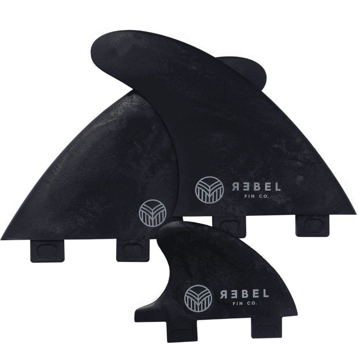Das Rebel Fin - Rapid Fin Set FCS I - Carbon von Rebel Fin enthält drei schwarze, karbonverstärkte Surfboard-Finnen mit weißen Logos in verschiedenen Größen, die überlappend auf weißem Grund abgebildet sind - ideal für stehende Wellen.