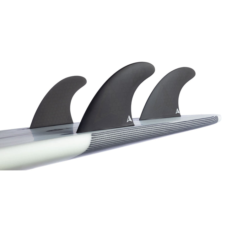 Seitliche Nahaufnahme von drei schwarzen ROAM Thruster Finnen Set Allround One Tab Finnen von Roam in einem Thruster Setup, befestigt an einem Surfboard mit weißen und grauen Streifen. Mit Single-Tab-Montage für sicheren Sitz und Allround-Performance.