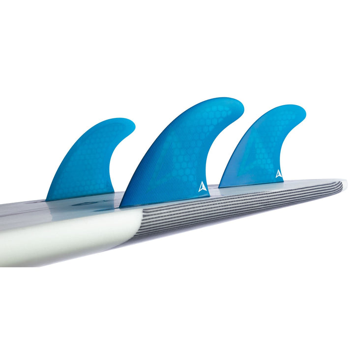 Eine Nahaufnahme eines weiß-grauen Surfboards mit dem Roam Thruster Fin Set Allround one tab und drei blauen Honeycomb-Finnen von Roam, die an Futures Finboxen befestigt sind.