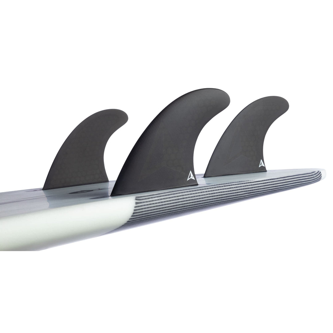 Nahaufnahme des Hecks eines Surfbretts, das mit drei schwarzen ROAM Thruster Fin Set Allround two tab fins von Roam ausgestattet ist, mit einem weiß-grau gestreiften Design auf der Unterseite des Bretts.