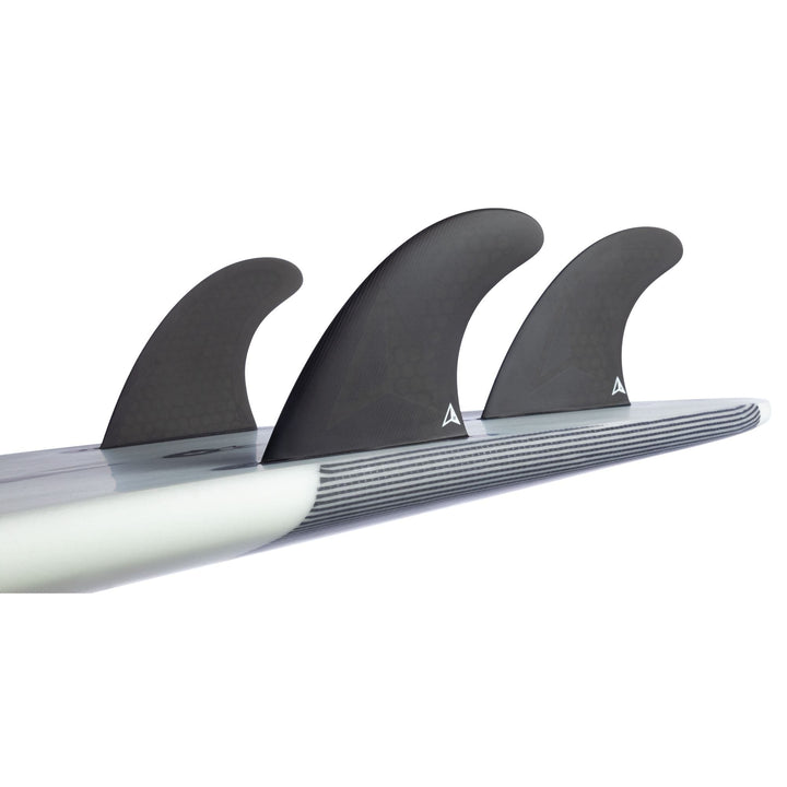 Nahaufnahme des Hecks eines Surfbretts, das mit drei schwarzen ROAM Thruster Fin Set Allround two tab fins von Roam ausgestattet ist, mit einem weiß-grau gestreiften Design auf der Unterseite des Bretts.