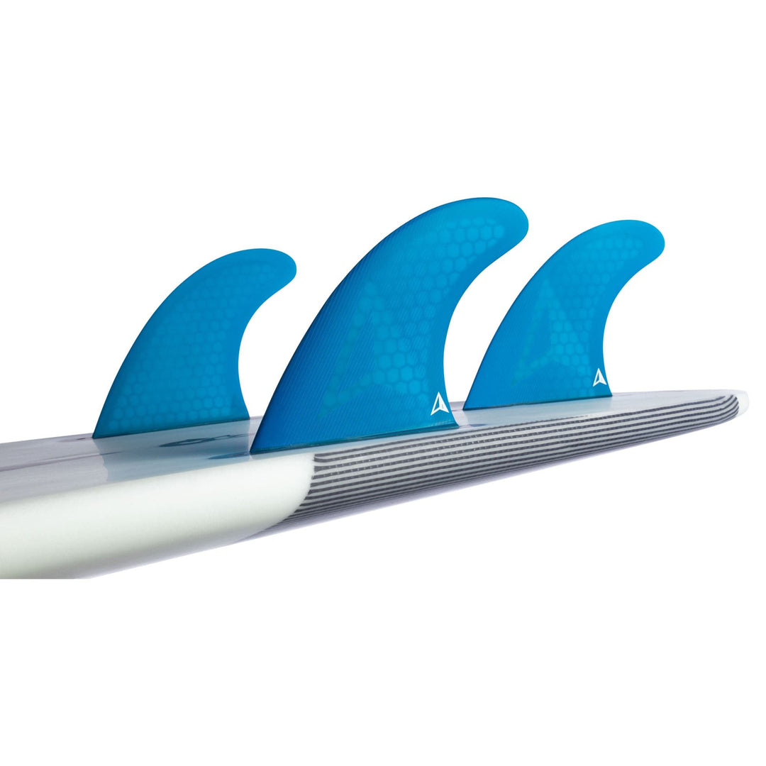 Eine Nahaufnahme von drei blauen ROAM Thruster Fin Set Allround two tab fins von Roam, die an der Unterseite eines weißen Surfbretts befestigt sind, aus einer schrägen Perspektive.