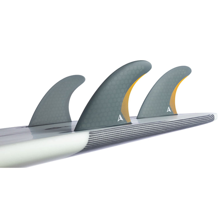 Eine Nahaufnahme des hinteren Teils eines Performance-Shortboards zeigt die Roam ROAM Thruster Fin Set Performer one tab-three graue Finnen mit Wabenmuster und gelben Akzenten, die am Boden befestigt sind.