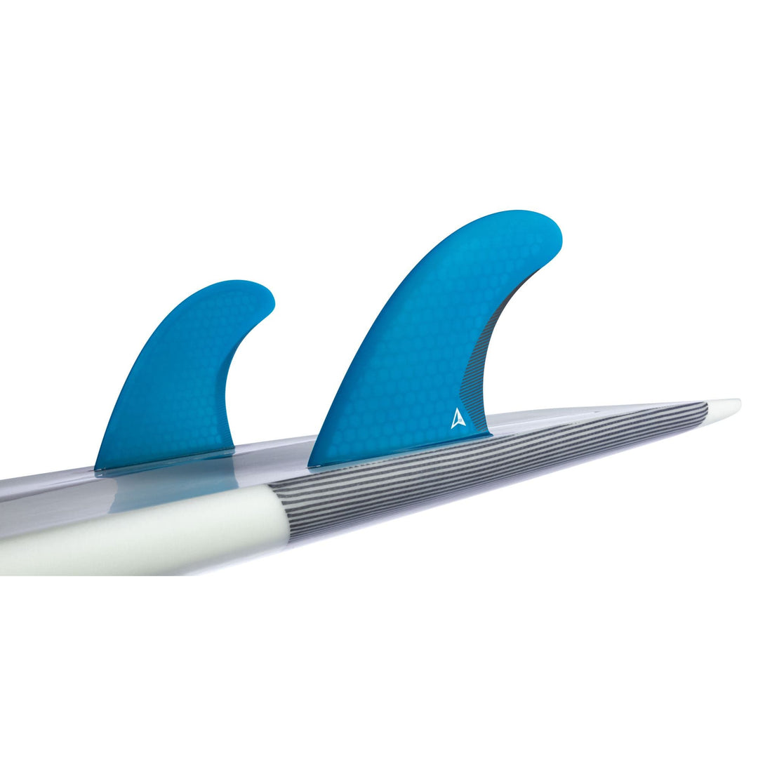 Eine Nahaufnahme eines Roam ROAM Twin Fin Set Medium one tab in blau, montiert in der Futures Finbox auf einem Surfbrett mit weiß-grau gestreifter Oberfläche.
