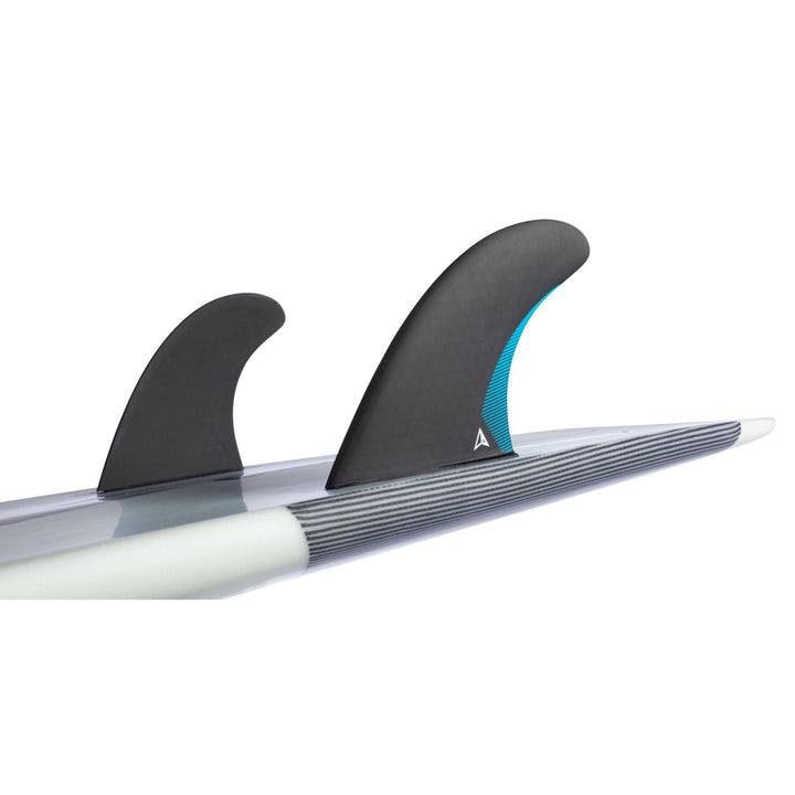 Nahaufnahme des ROAM Twin Fin Set Medium one tab von Roam mit Wabenkonstruktion und einer blau akzentuierten Finne. Montiert in Futures Finnenkästen, ergänzen diese Flossen das weiße und graue Design des Surfboards.