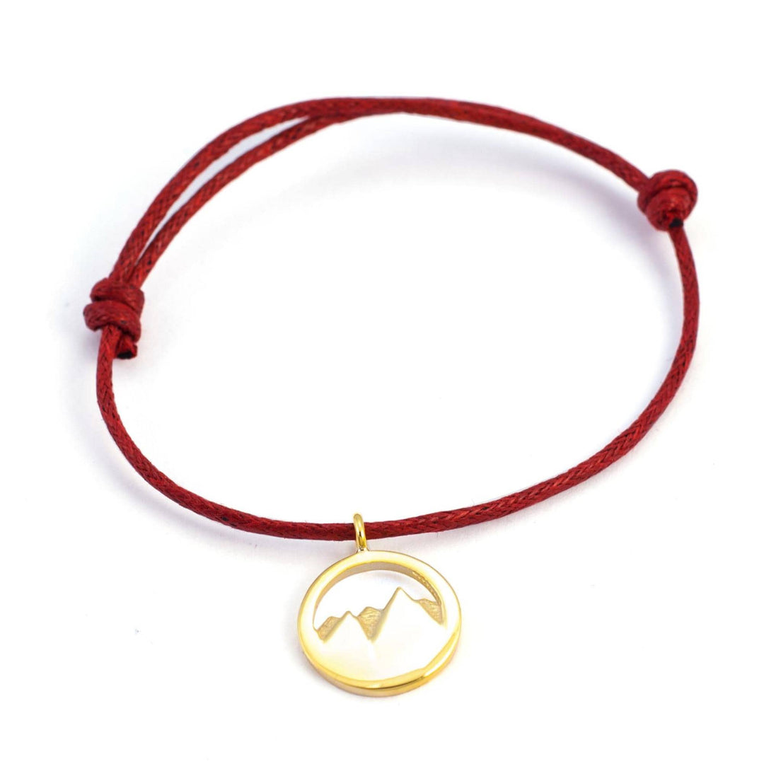 Das Silver+Surf Silber Schmuck Berg 3D vergoldet ist ein rotes Kordelarmband mit verstellbaren Knoten und einem kreisförmigen 3D-Berganhänger in Gold von Silver+Surf.