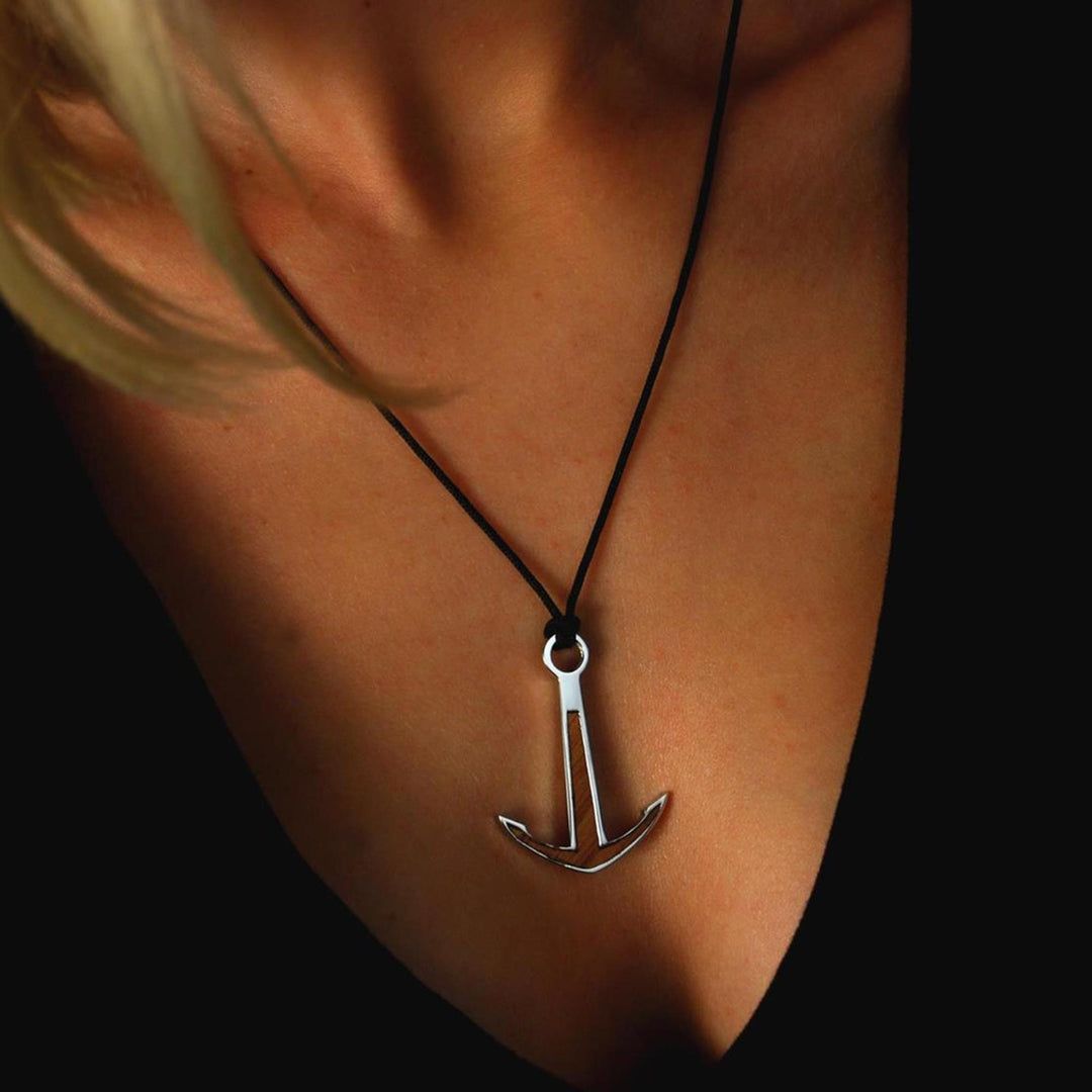 Eine Nahaufnahme einer Person, die ein schwarzes Oberteil und das Silver+Surf Silber Schmuck BootAnker Wood Halsband trägt. Der Silber+Surf-Anhänger liegt in der Mitte der Brust, Hals und Schlüsselbein sind teilweise sichtbar.
