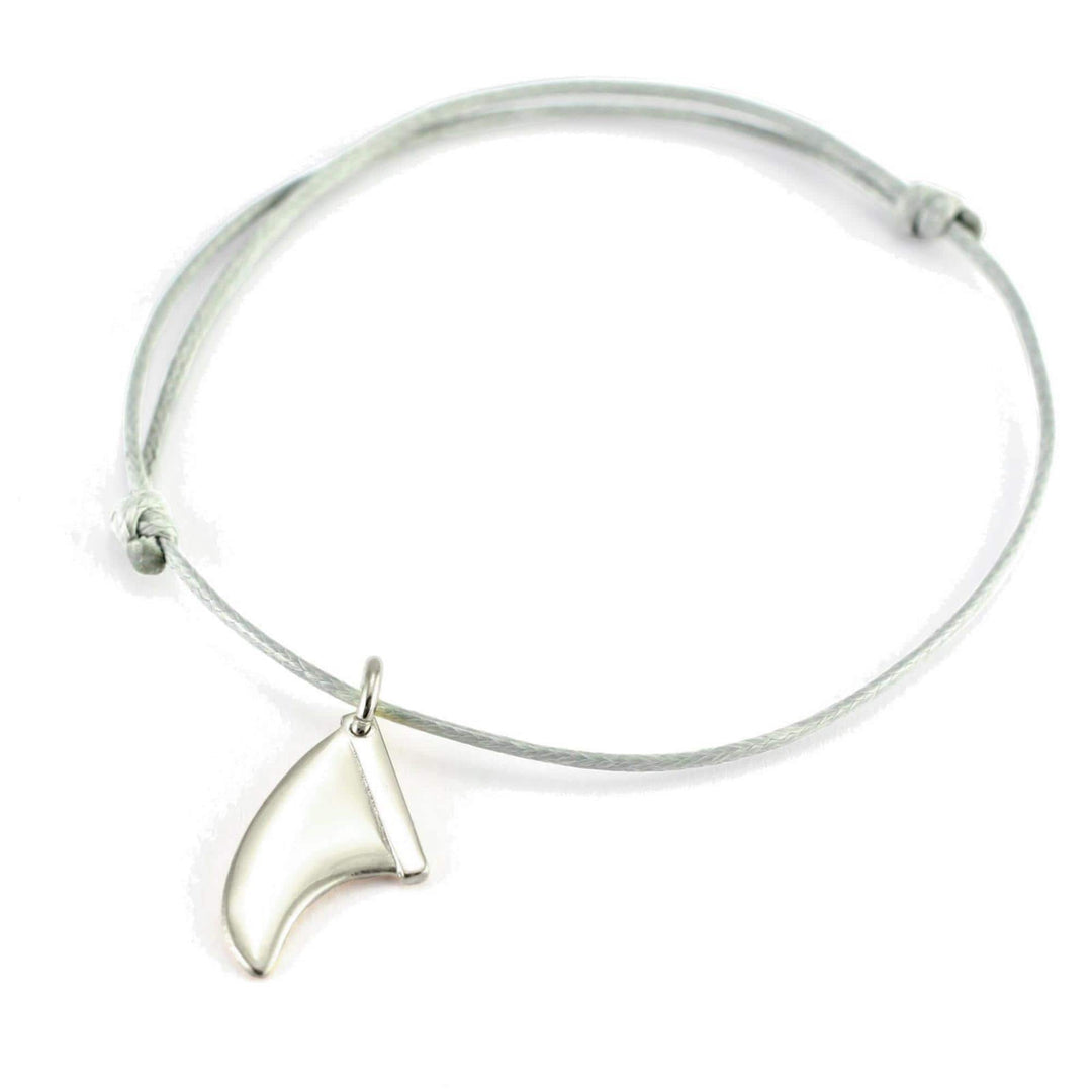 Ein minimalistisches Armband mit einer dünnen hellgrauen Kordel und verstellbarem Knoten, mit einem kleinen Silber+Surf Silber Schmuck Surfboard Finne Anhänger aus 925 Sterling Silber.