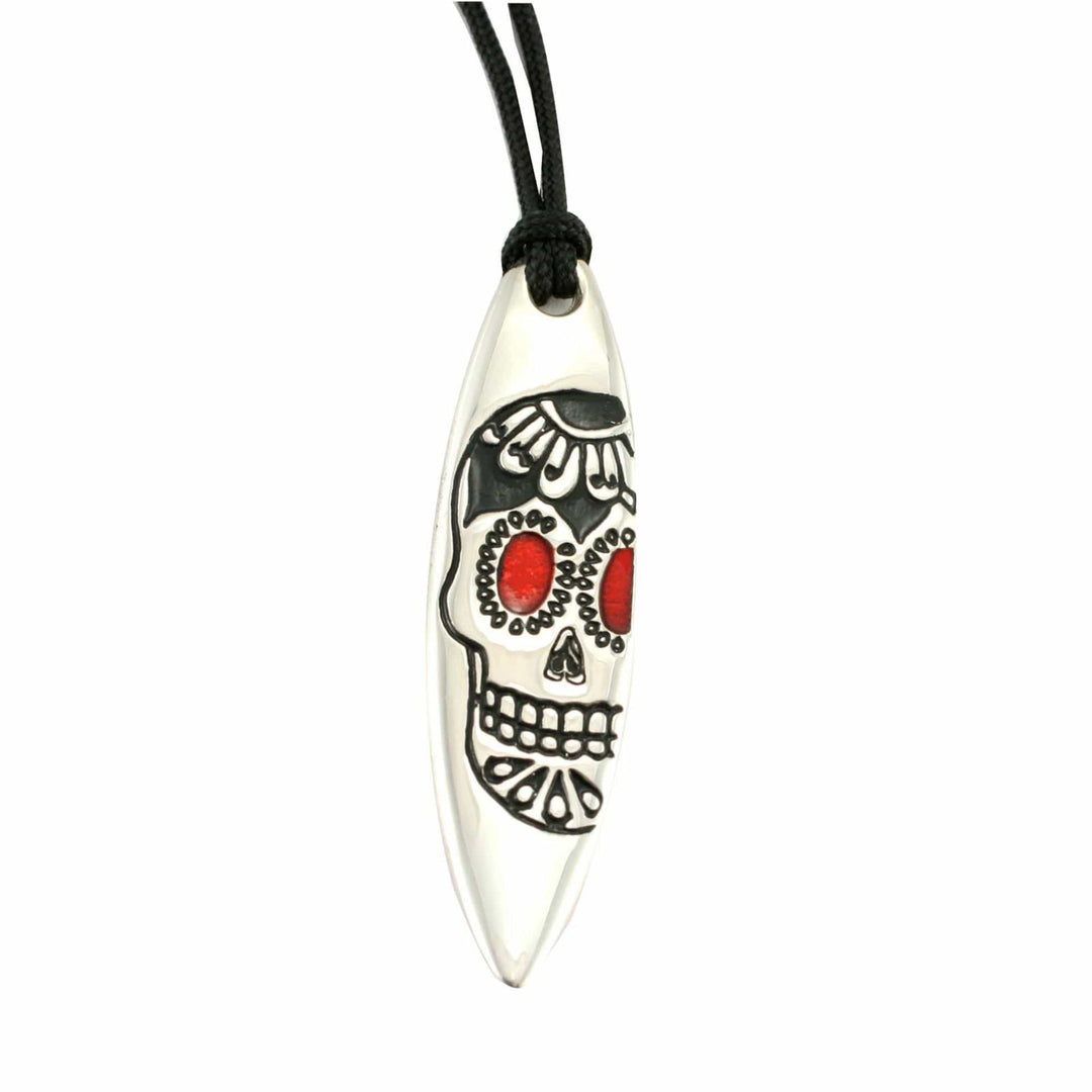 Der Silver+Surf Silber Schmuck Surfboard mit Totenkopf von Silver+Surf besteht aus einem ovalen Anhänger aus 925er Sterling Silber an einer schwarzen Kordel, der mit einem Totenkopfdesign mit schwarzen Konturen und auffälligen roten Augen versehen ist.