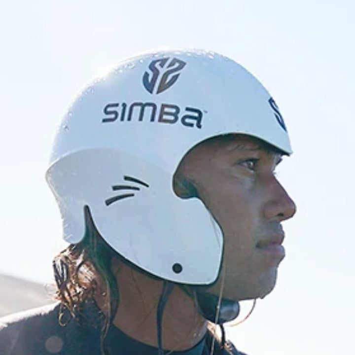 Eine Person mit nassem, schulterlangem Haar trägt einen weißen Simba Surf SIMBA Surf Wassersport Helm Sentinel, der hervorragenden Aufprallschutz für die Seiten und den Hinterkopf bietet. Der helle Hintergrund deutet auf einen Außenbereich hin, wenn sie nach rechts schauen.