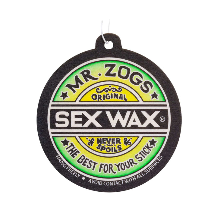 Der SEX WAX Lufterfrischer Lufterfrischer von SEX WAX hat ein kreisförmiges Design mit den Farben grün, gelb, schwarz und weiß, den Text "Never Spoils" und "The Best for Your Stick" und eine weiße Schnur - ideal für Autos oder Surfausrüstung.
