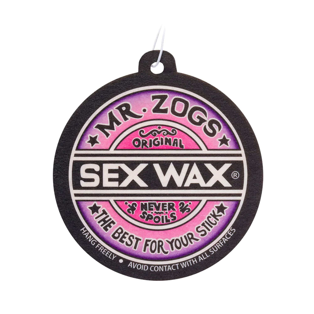 Der SEX WAX Lufterfrischer von SEX WAX ist ein runder Lufterfrischer mit einem Loch an der Spitze, auf dem "Mr. Zogs Original Sex Wax Never Spoils The Best For Your Stick" auf einem rosa und schwarzen Hintergrund steht.