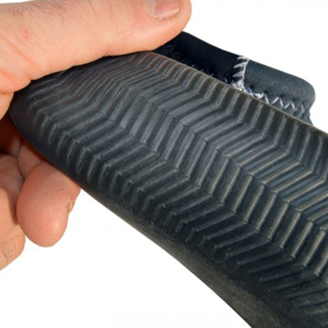 Eine Hand hält den ATAN Madi Neopren Latex Halbschuh 3mm von Atan und zeigt seine dunkle Gummisohle mit Fischgrätprofil, sichtbaren Randnähten und Barfusstechnologie - perfekt für Windsurfen und Wassersport.