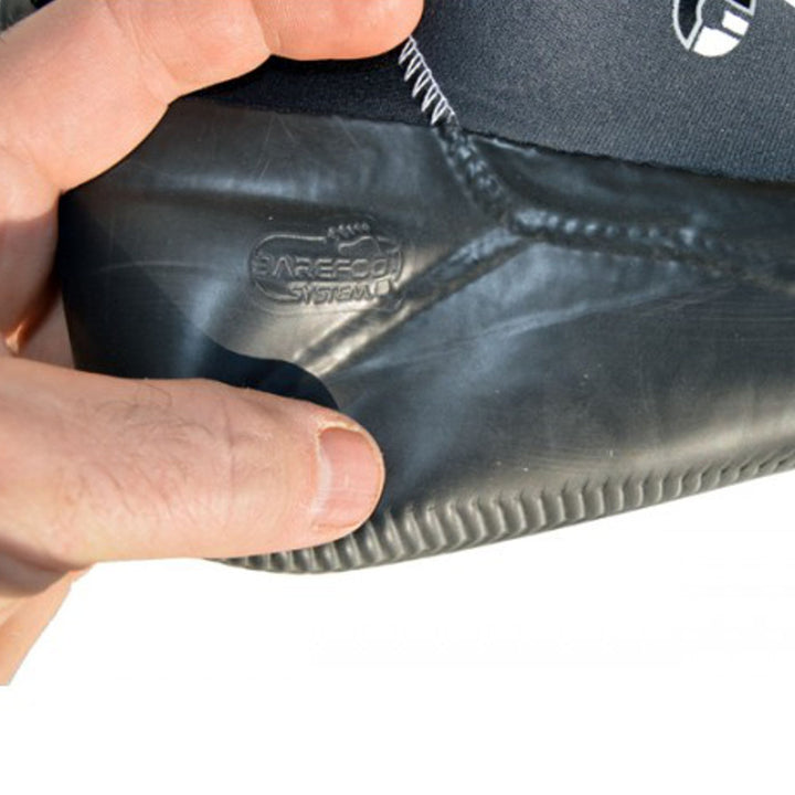 Eine Hand hält die Ferse eines Atan ATAN Madi Neopren Latex Halbschuh 3mm Wasserschuhs mit sichtbaren Nähten und "Barefoot System" Prägung an der Seite, die die fortschrittliche Barfußtechnologie für das Windsurfen hervorhebt.
