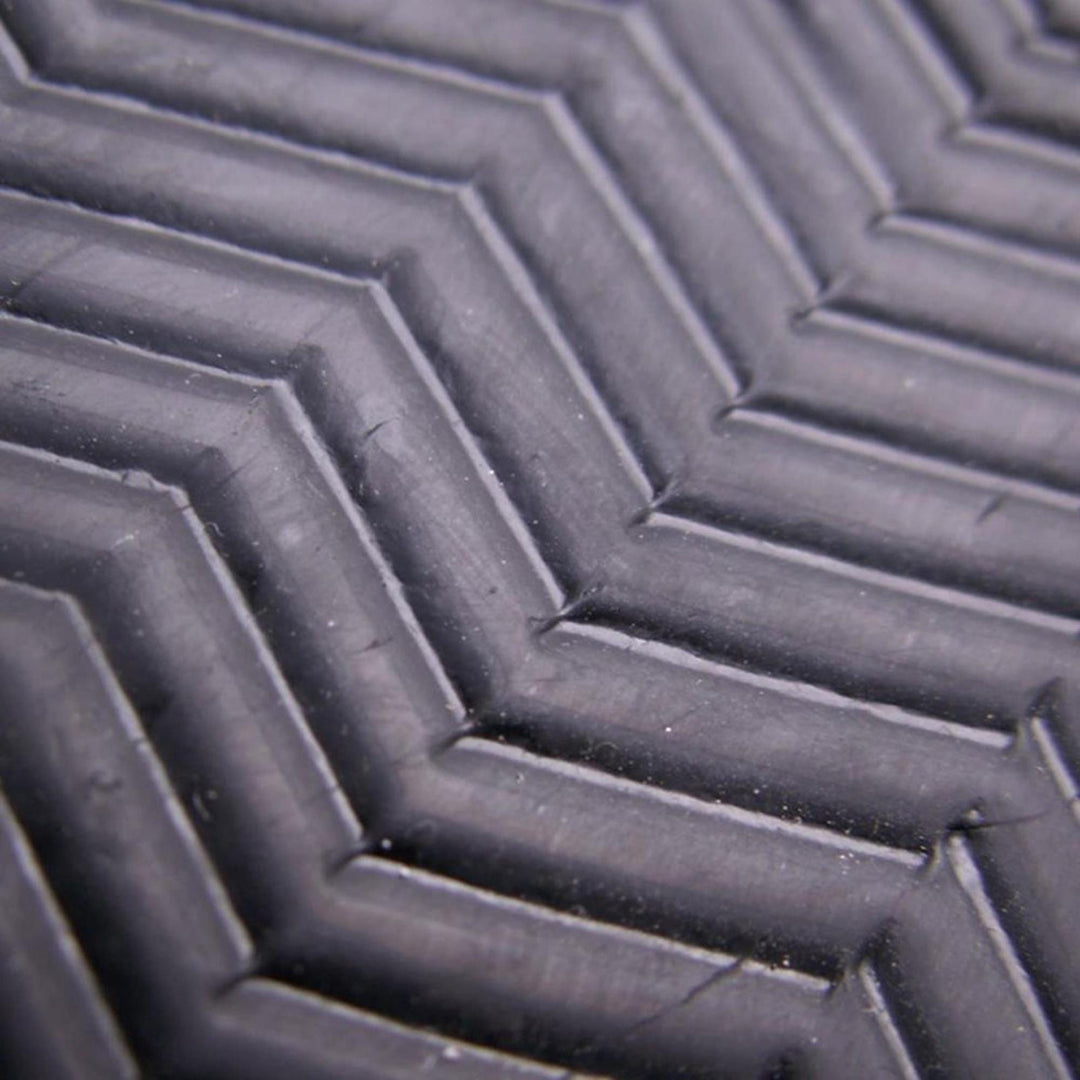 Nahaufnahme einer schwarzen Oberfläche mit einem erhabenen Chevron-Muster, wie der Griff des Atan ATAN Madisson Neopren Latex Schuh 3mm. Sein strukturiertes Gummi hebt die präzise Barfusstechnologie durch geometrische Linien und Rillen hervor.