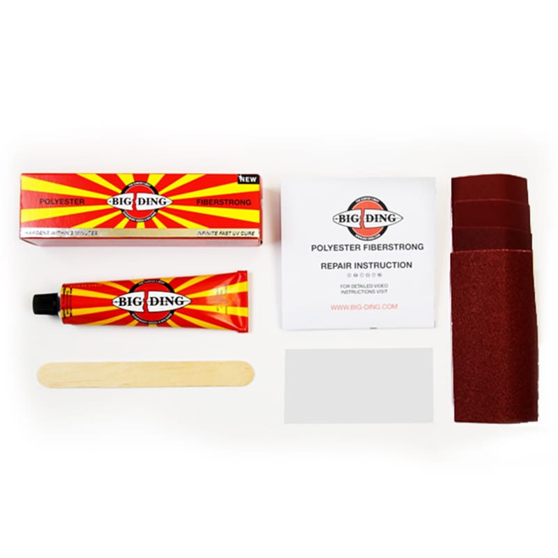 Ein Surfbrett-Reparaturset enthält eine Tube Big Ding UV Cure Polyester Fiberstrong, Schleifblätter, einen Mischstab, ein Glasfasertuch und eine Reparaturanleitung, alles auf einer weißen Fläche.