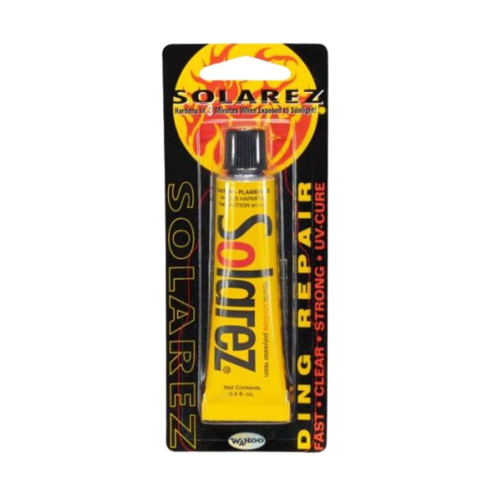 Eine gelbe Tube Solarez - Polyester Weenie Ding Repair (0,5oz/14,75ml) in schwarz-gelber Verpackung mit Flammengrafik - schnelles, klares UV-härtendes Harz, ideal für Surfbrett- oder Polyesterreparaturen. Marke: Solarez.