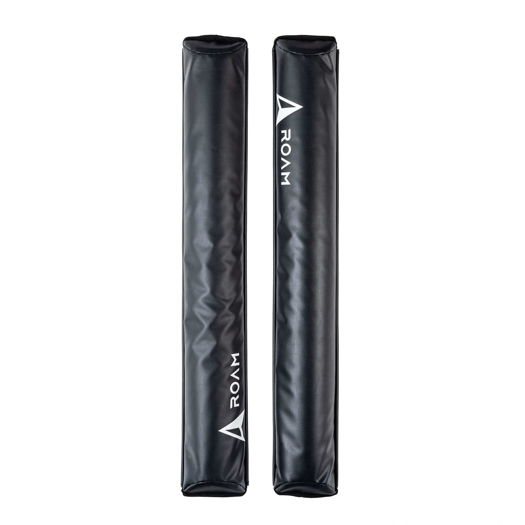 Zwei schwarze rechteckige ROAM Dachauflage Surfboard Flach Polster Pads von Roam, jeweils mit "ROAM" und einem weißen Dreieckslogo. Vertikal auf weiß abgebildet, verfügen sie über einen Klettverschluss zur einfachen Befestigung am aerodynamischen Dachträger.