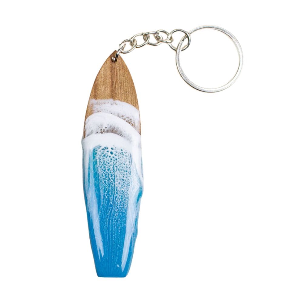 Der Surfboard Schlüsselanhänger handgefertigt von Takemetotheocean besteht aus einem surfbrettförmigen Holzanhänger mit blau-weißem Resin Ocean Art Wellen-Design und ist an einem Metallring befestigt.