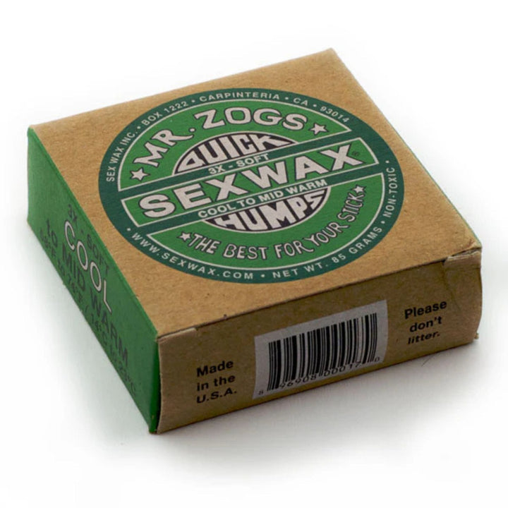 Eine Pappschachtel mit SEX WAX - Quick Humps Surfwachs von SEX WAX, beschriftet mit 3X Soft mit grünem und weißem Text. Enthält Produktdetails, Barcode, Website-Infos und Kokosnuss-Duft für verbesserten Grip auf dem Board.