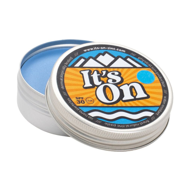 Eine runde Metalldose mit einem teilweise geöffneten Deckel enthüllt im Inneren den blauen "It&