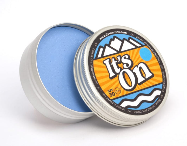 Eine runde Dose mit teilweise geöffnetem Deckel zeigt im Inneren den blauen It&