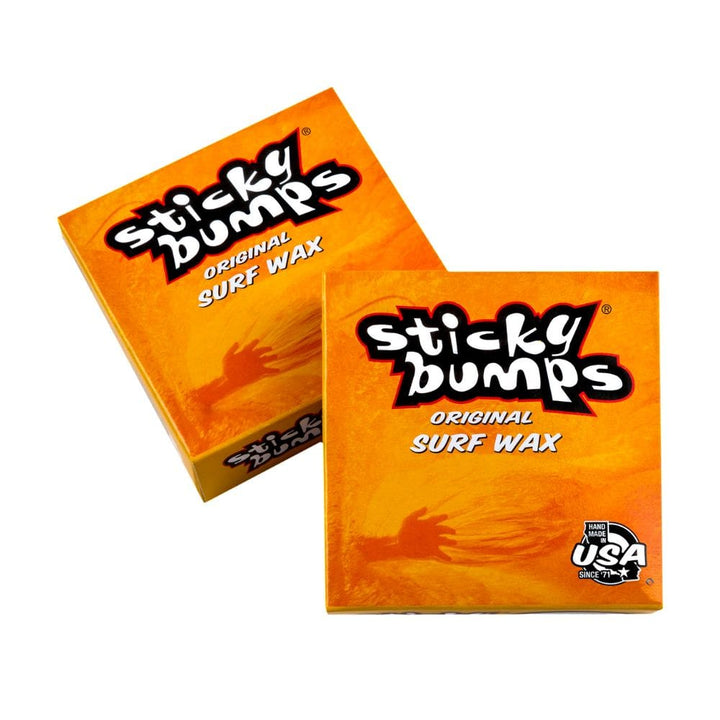 Abgebildet sind zwei orangefarbene Sticky Bumps - Surfwachs-Boxen mit fettgedruckter weißer und schwarzer Schrift, einem Made in USA-Symbol und zuverlässigem Surf-Grip mit biologisch abbaubaren Inhaltsstoffen.