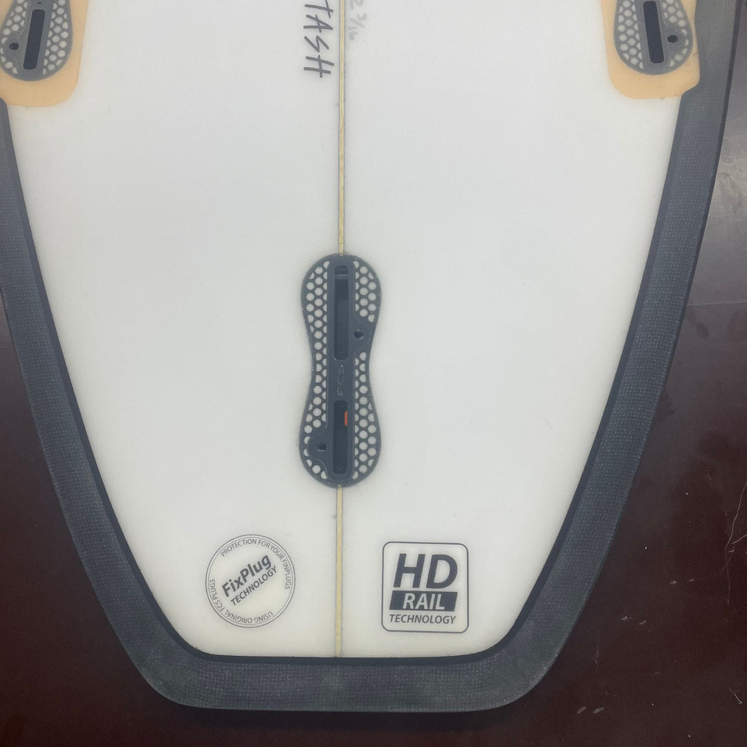 Eine Nahaufnahme des Hecks des Delight Alliance - Stash Riversurfboards zeigt einen mittleren Finnenschlitz, zwei äußere Finnenplugs, eine schwarze Schiene und Aufkleber mit der Aufschrift "HD Rail Technology" und "Futures - Fin Plug Technology".
