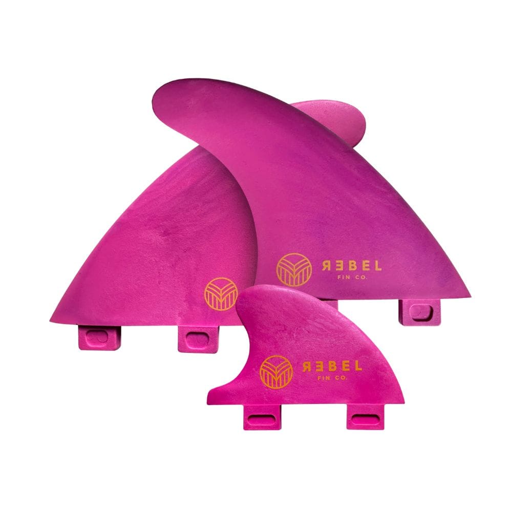 Das Rebel Fin - Rapid Fin Set FCS I in pink von Rebel Fin besteht aus drei Glasfaserflossen mit gelbem Branding, ideal für stehende Wellen. Auf einem weißen Hintergrund präsentiert, ist dieses Set perfekt für das Rebel Fin Thruster Setup.