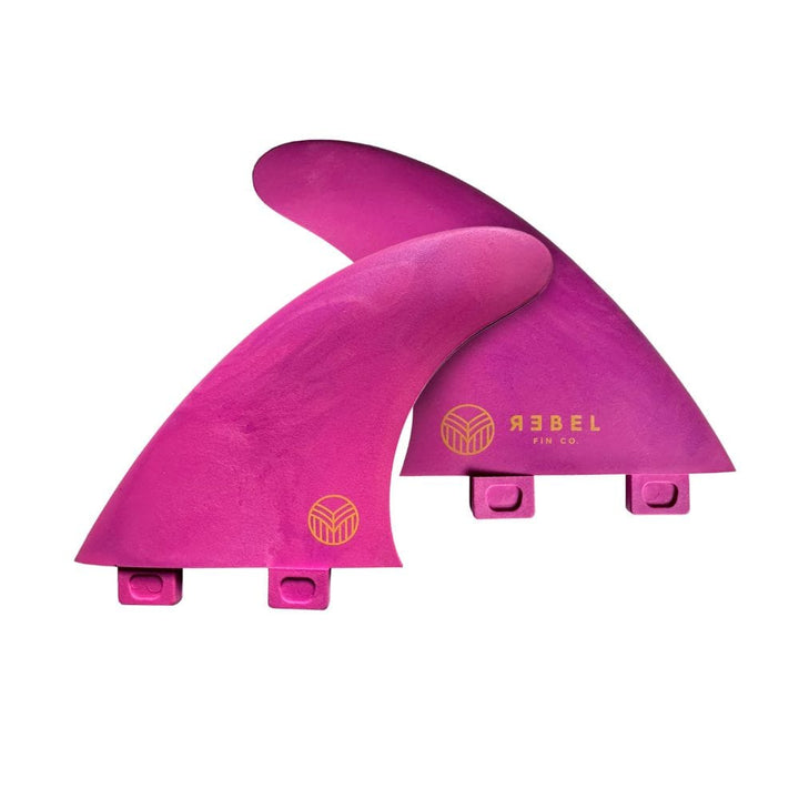 Das Rebel Fin - Twin Set Glasfaser pink besteht aus zwei rosafarbenen Flossen mit dem Rebel Fin Logo und gelbem Text. Zwei Laschen an der Basis ermöglichen eine einfache Befestigung, wobei eine Flosse die andere teilweise überlappt.