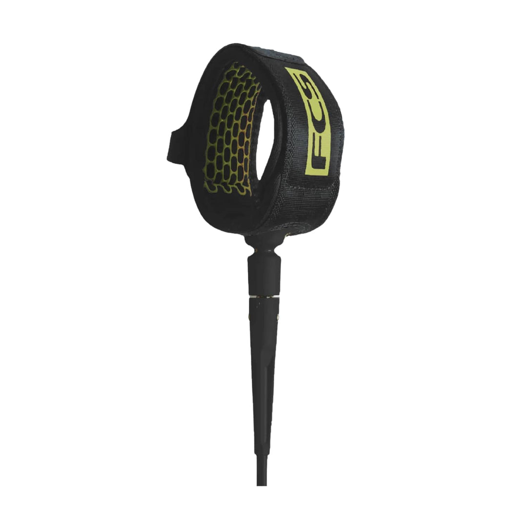 Die FCS Comp Essential Leash 5ft ist eine schwarze Surf-Leash mit einem gepolsterten Knöchelriemen mit gelbem Wabenmuster und FCS-Logo sowie einer verstärkten Verbindung für Flusssurfen und dynamische Sessions.