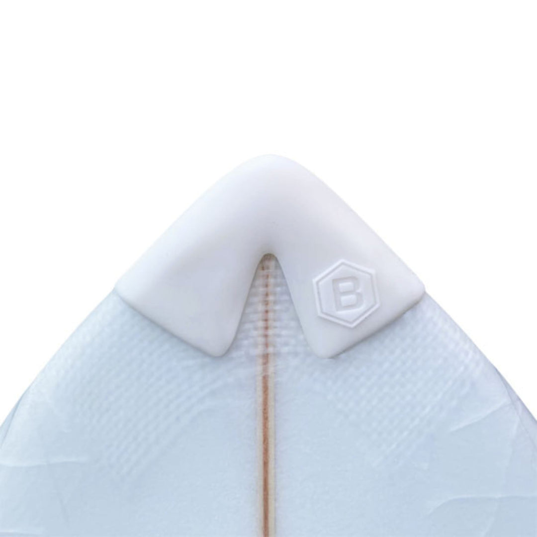 Nahaufnahme eines Buster-Surfboards-Surfbretts mit weißem Buster Surfboards Noseguard und sechseckigem "B"-Emblem an der Spitze; der Holzstringer des Bretts ist in der Mitte sichtbar.